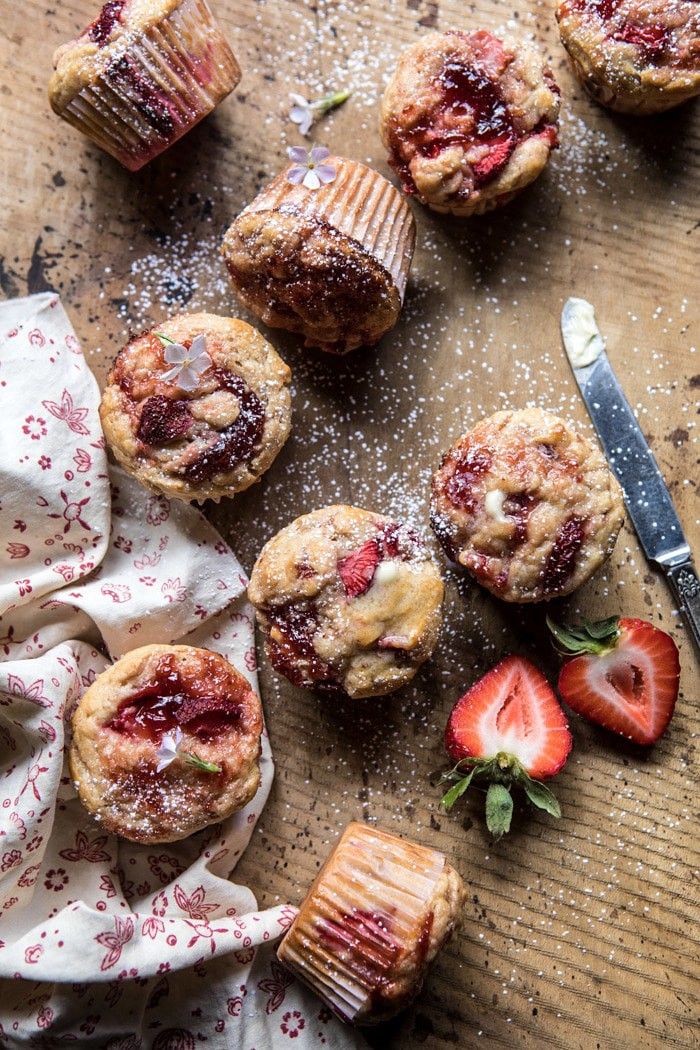 strawberry muffins with powdered sugar and fresh strawberries on the table next to them