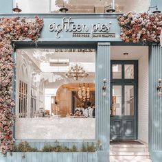 a store front with flowers on the outside