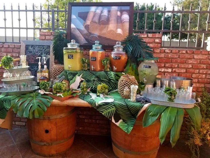 there are many plants and jars on the table together in front of a brick wall