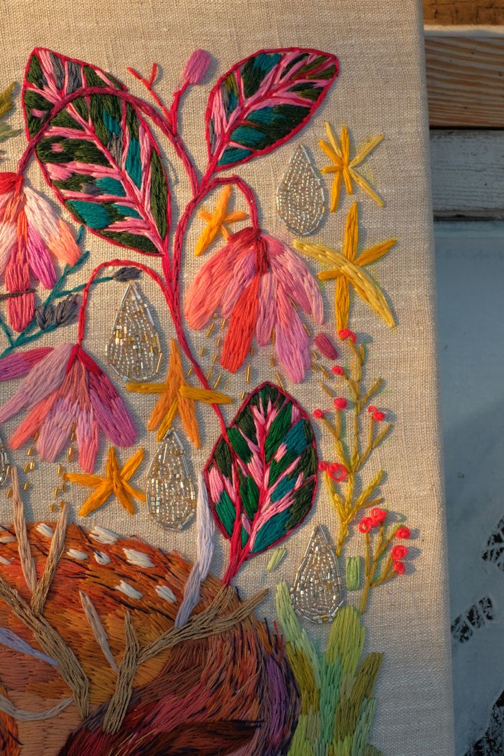 an embroidered piece of art with flowers and leaves