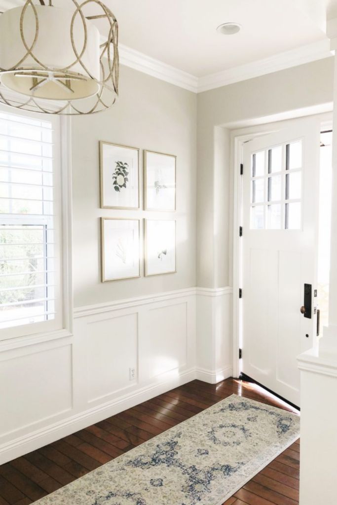 a hallway with white walls and wooden floors, framed pictures on the wall, and a rug