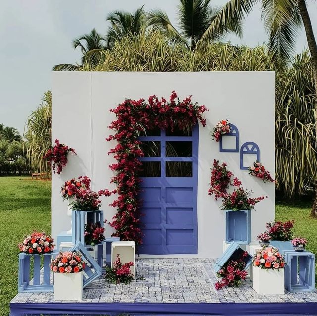 a blue and white house with flowers on the front door is decorated for an outdoor ceremony