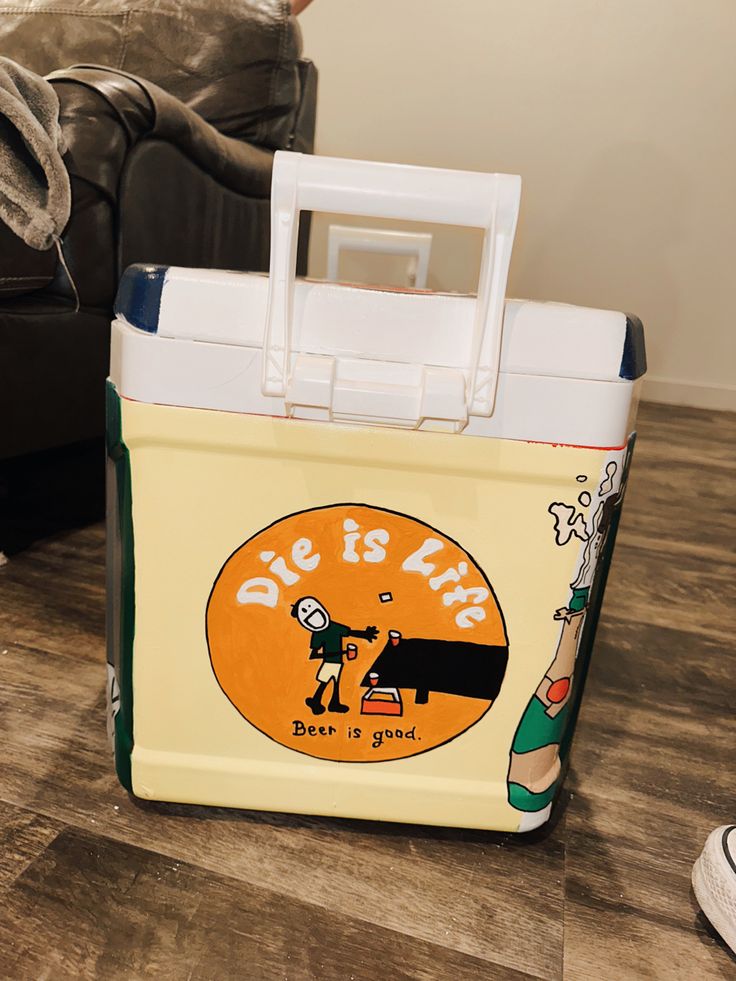 a yellow and white cooler sitting on top of a wooden floor next to a couch