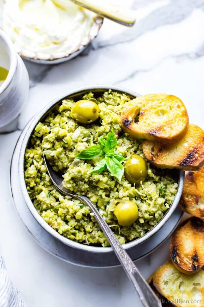 a bowl filled with rice and olives on top of a table next to bread