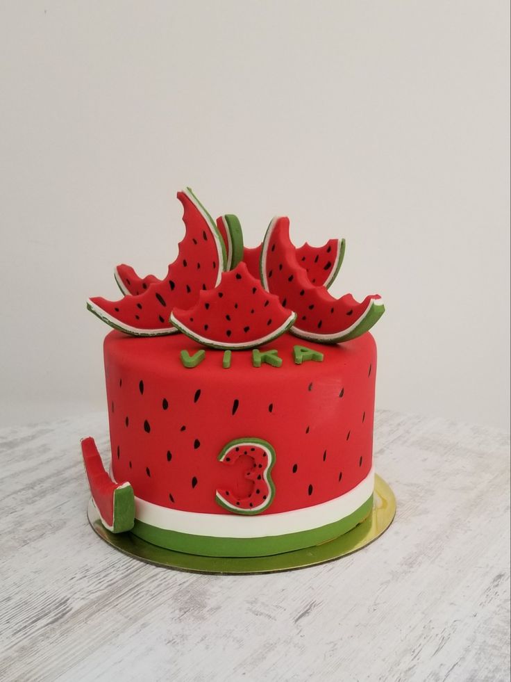 a red cake with watermelon slices on top is sitting on a white table