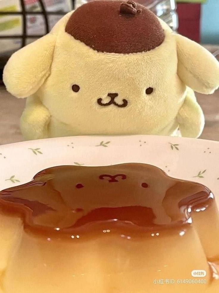 a stuffed animal sitting next to a plate with jelly on it