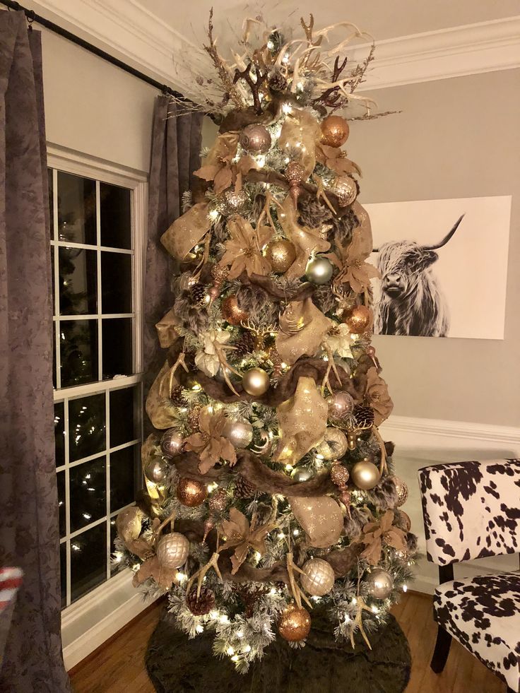 a christmas tree decorated with gold and silver ornaments in the corner of a living room