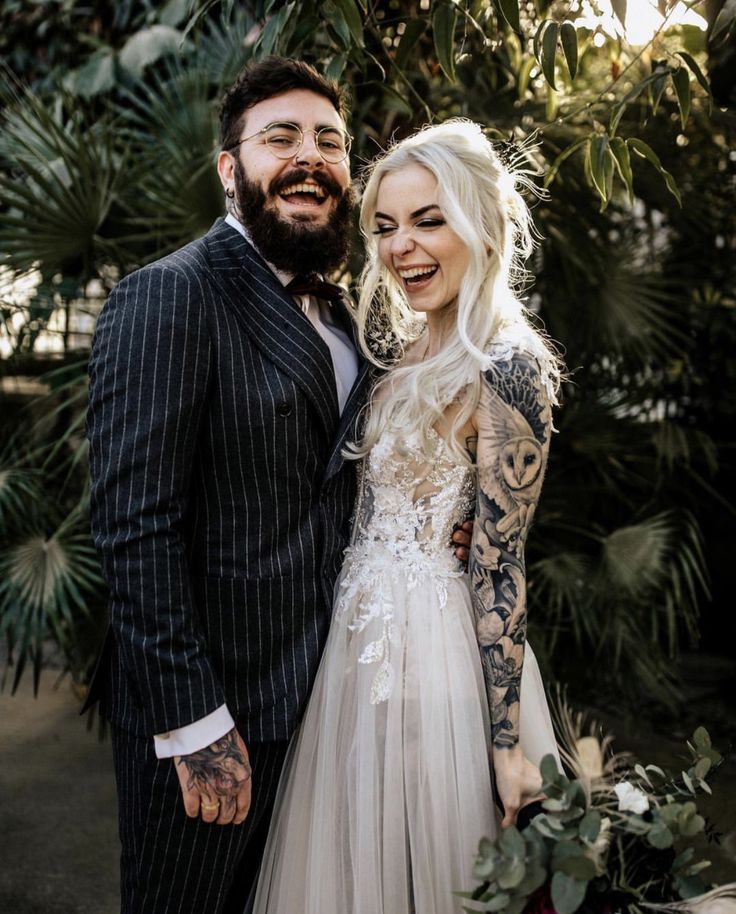 a tattooed bride and groom pose for a photo