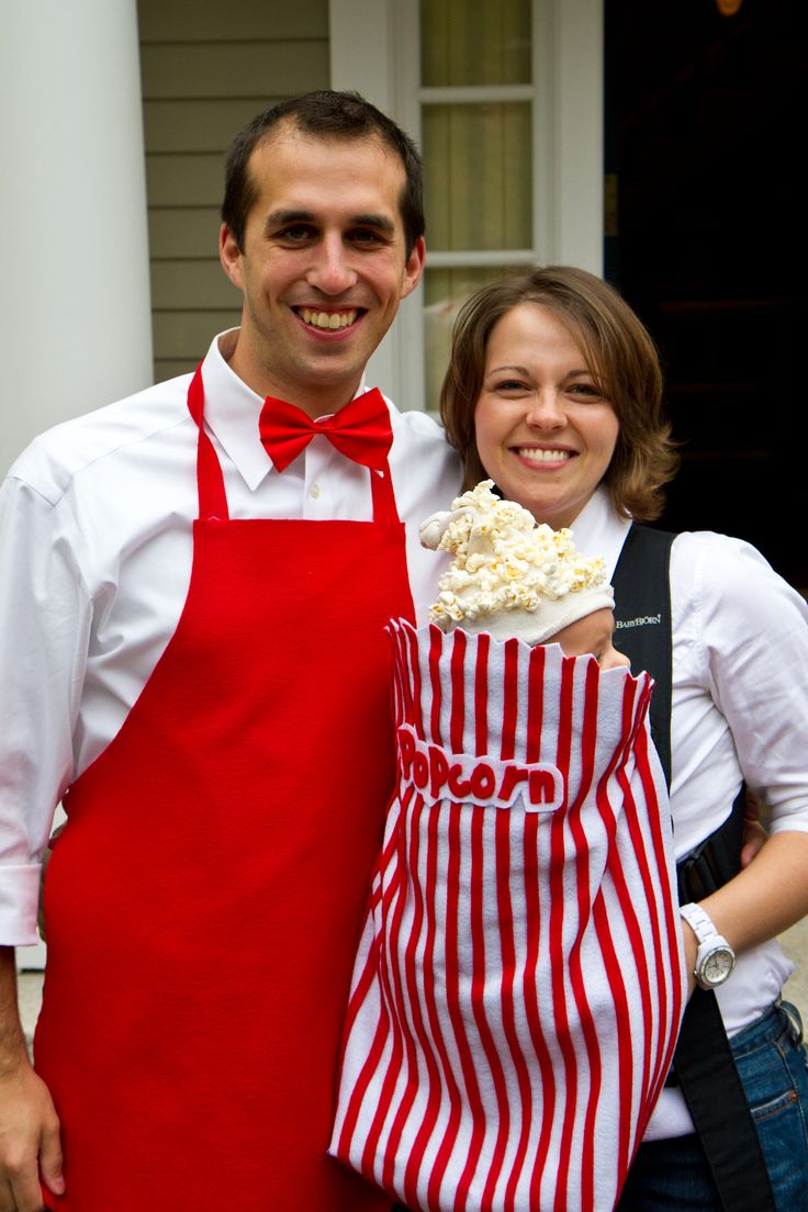 the man and woman are dressed up in red aprons, one is holding a cake