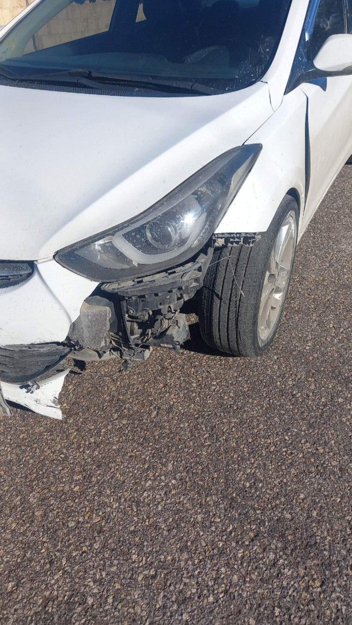 the front end of a white car that has been badly damaged