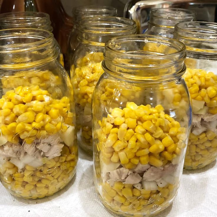 several glass jars filled with corn on top of a table