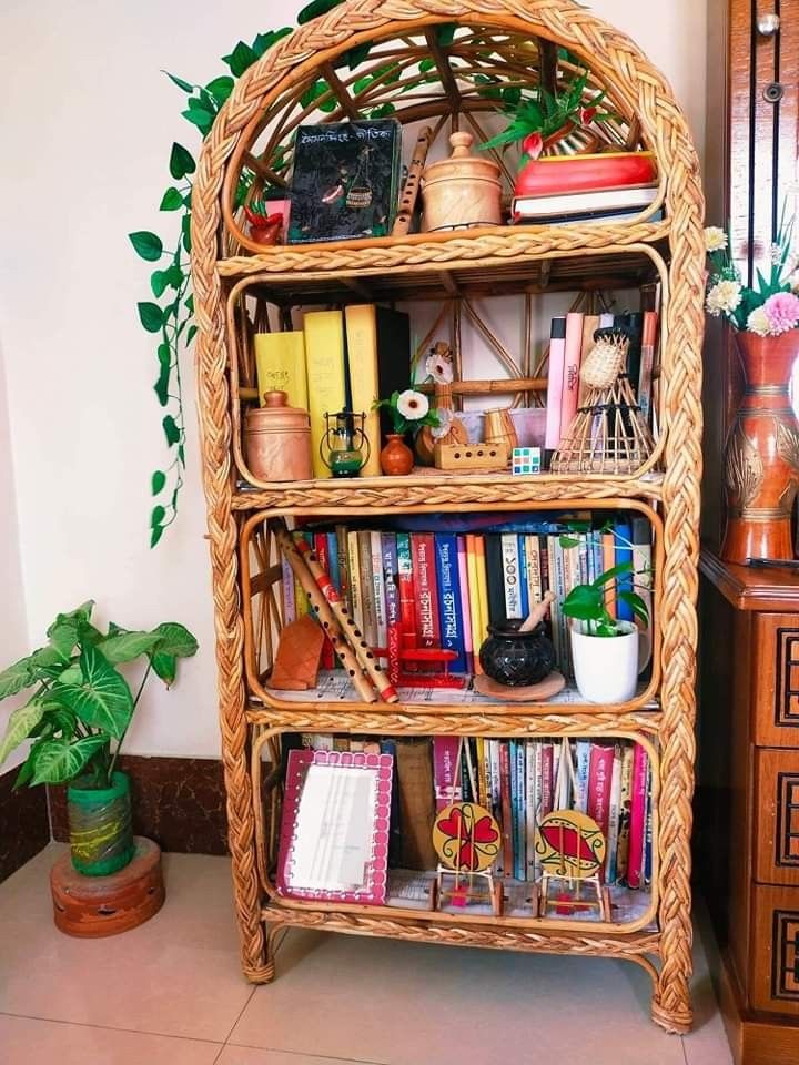 a wicker bookshelf filled with lots of books next to a potted plant