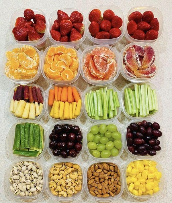 an assortment of fruits and vegetables in plastic containers on a counter top with almonds