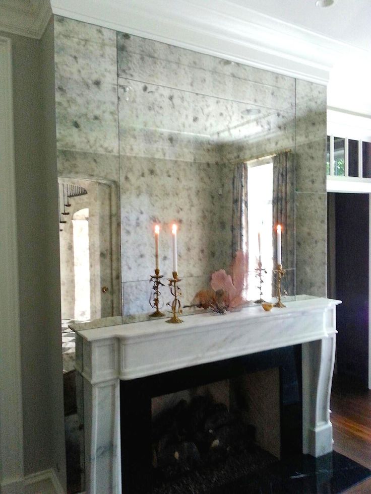 a living room with a fireplace and mirror on the wall