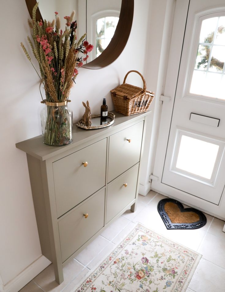 a vase filled with flowers sitting on top of a wooden dresser next to a door