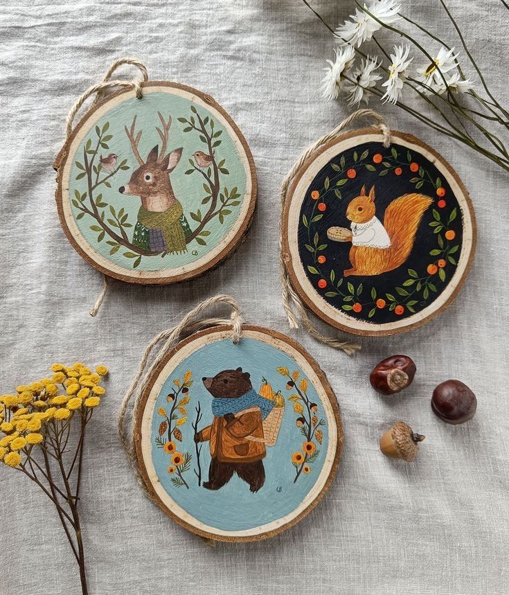 three wooden ornaments with animals on them and flowers in the foreground, along with other decorations