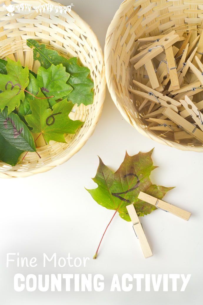 two baskets filled with green leaves and wooden clothes pins on top of a white table