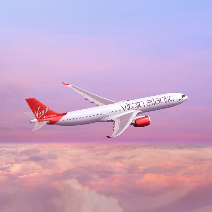 a virgin atlantic airplane flying in the sky with clouds around it and pinkish blue skies