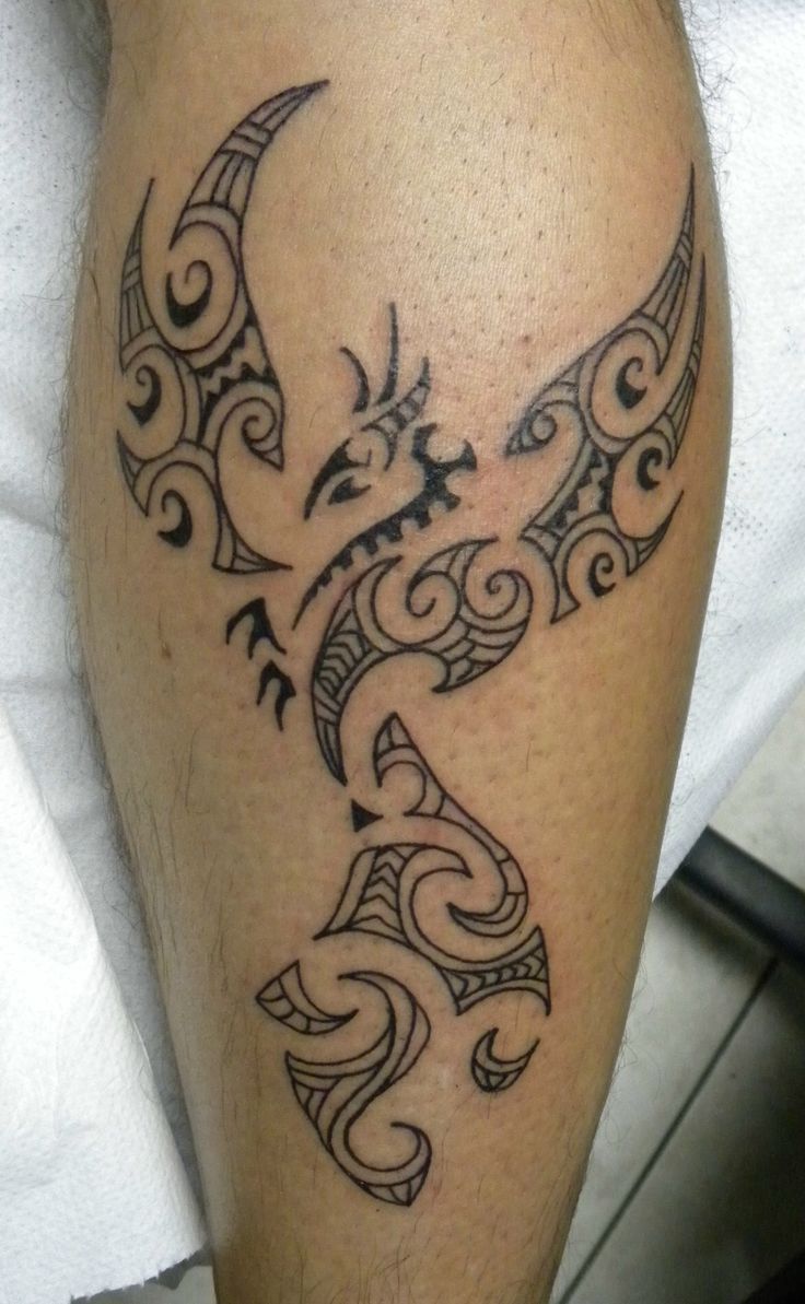 a tattoo on the leg of a man with an intricate bird and swirls design