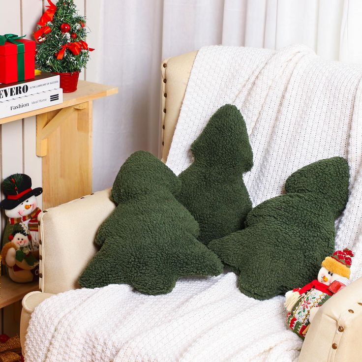 two green stuffed animals sitting on top of a white chair next to a christmas tree