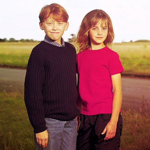 two young boys standing next to each other in front of a river and grassy field