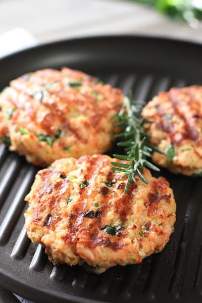 three crab cakes are cooking on a grill