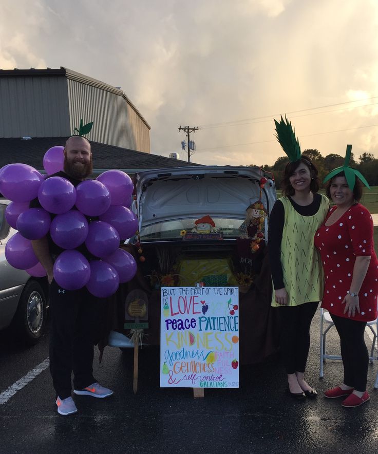 two women and a man are standing next to a car with balloons in the trunk