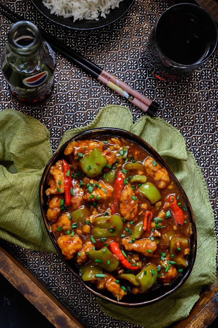 a bowl filled with chicken and peppers next to rice