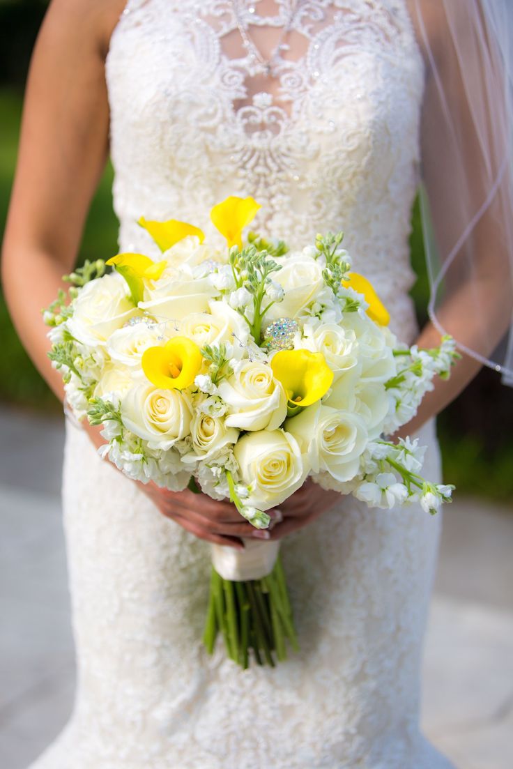 a bride holding a bouquet of white and yellow flowers