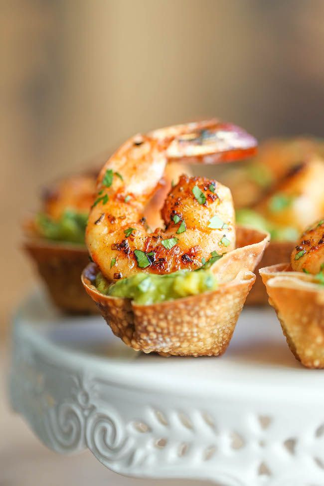 small cups filled with shrimp and guacamole on a white platter, ready to be eaten