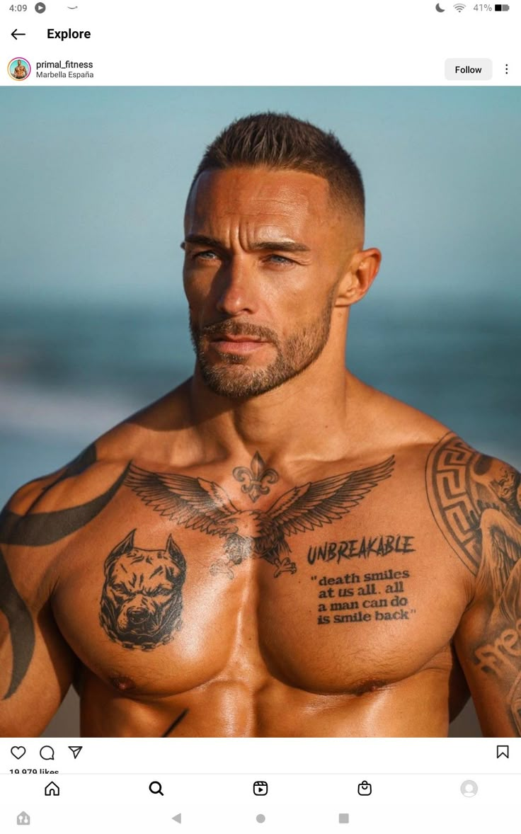 a man with tattoos on his chest standing next to the ocean and looking off into the distance