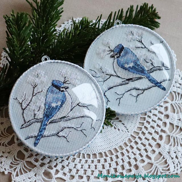 two blue birds sitting on top of a white doily next to a pine tree