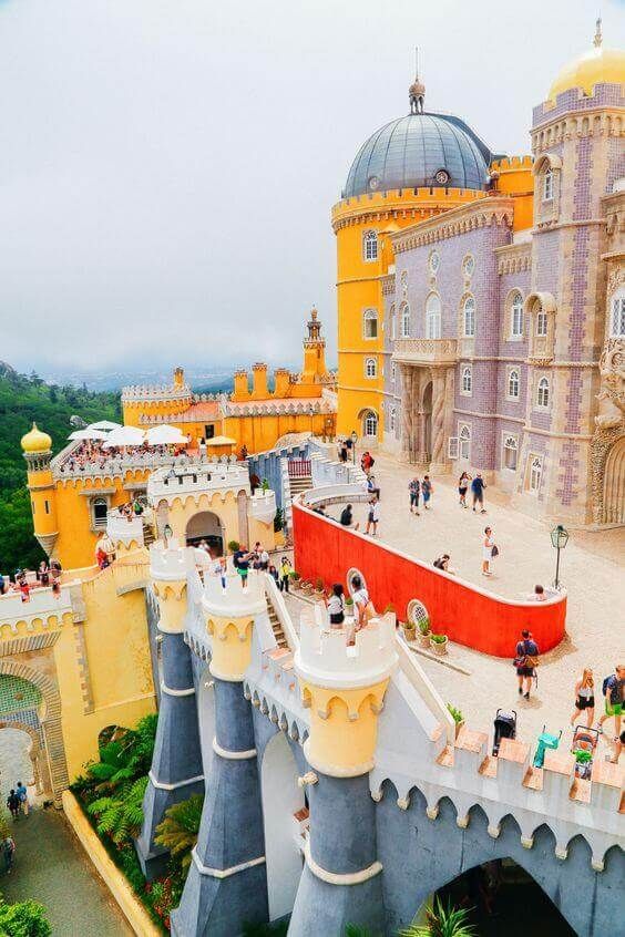 an aerial view of a castle with lots of people on the walkway and in front