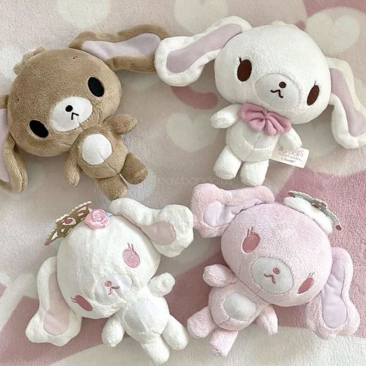 four stuffed animals are laying on a pink blanket