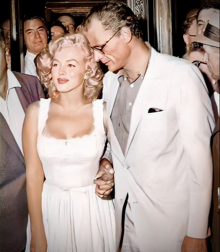 a man standing next to a woman in a white dress