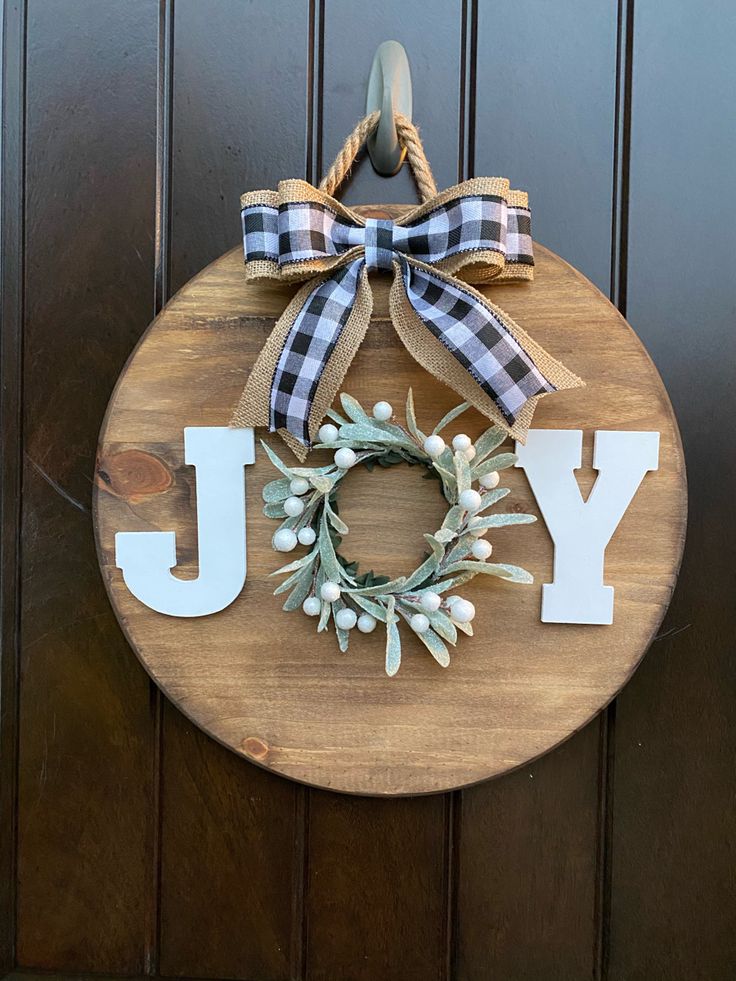 a wooden sign that says joy with a wreath on it and the word joy spelled out in large letters