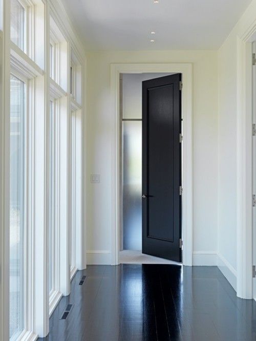 an empty hallway with white walls and black door