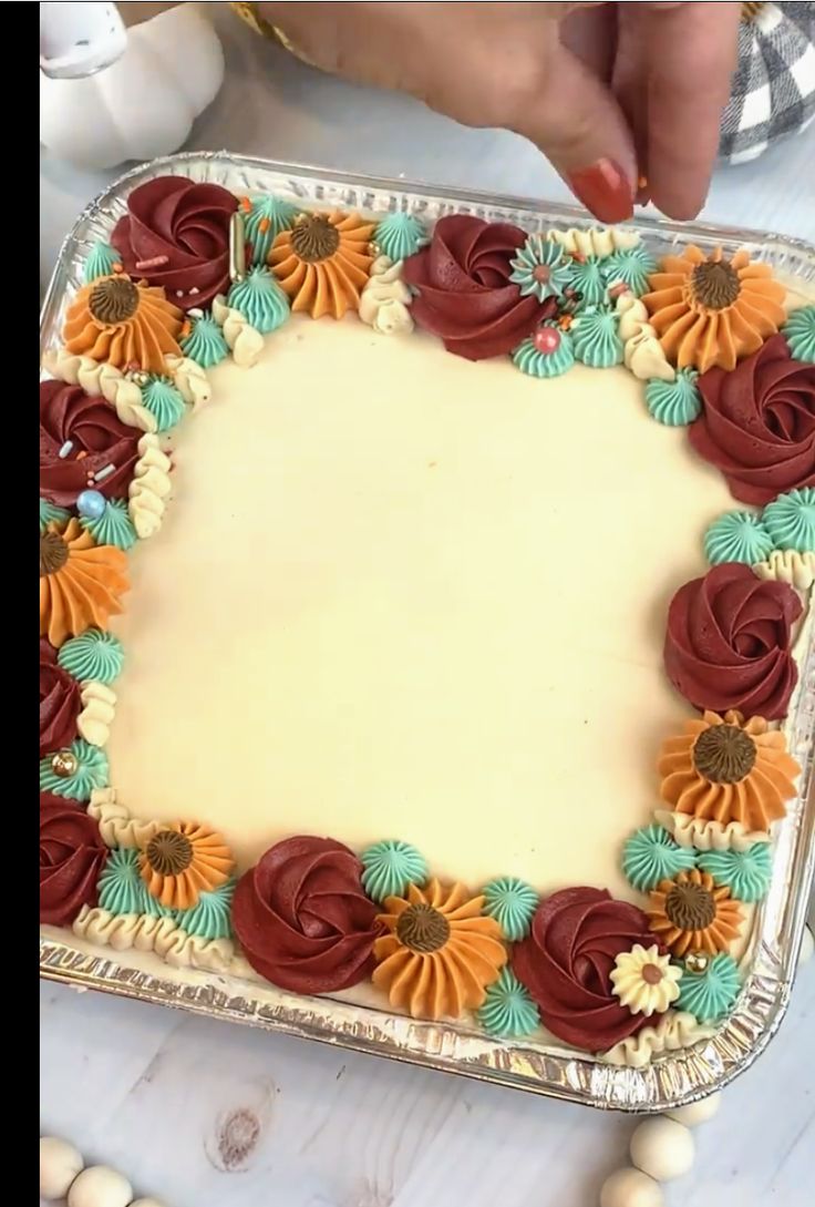 a cake decorated with flowers and icing on a table in front of a woman's hand