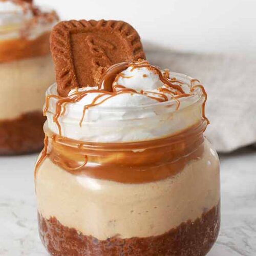 two dessert jars with cookies and whipped cream in them