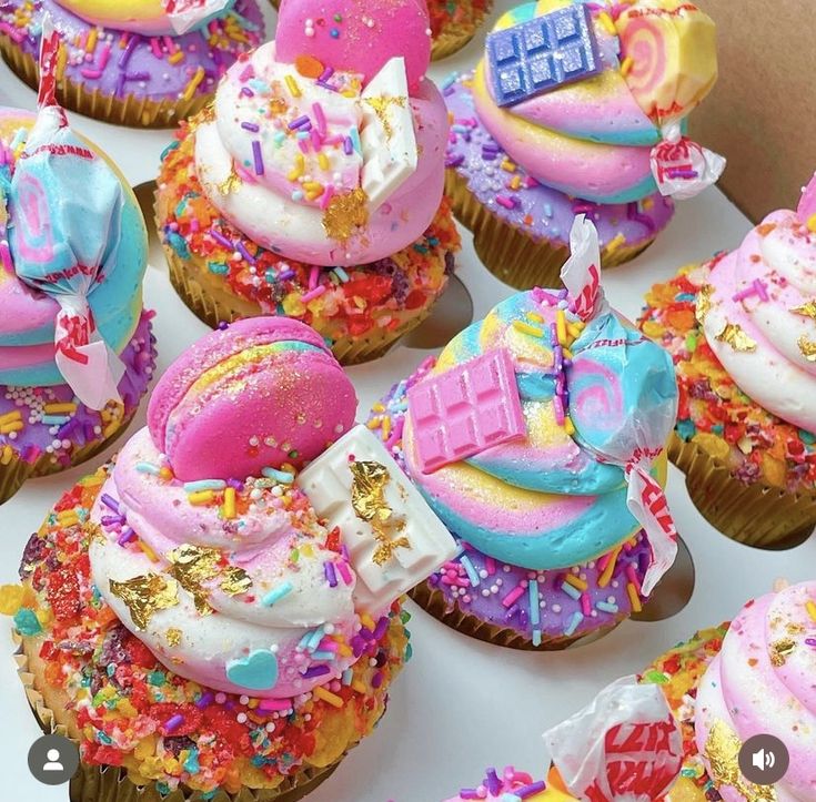 cupcakes decorated with colorful frosting and sprinkles are on display