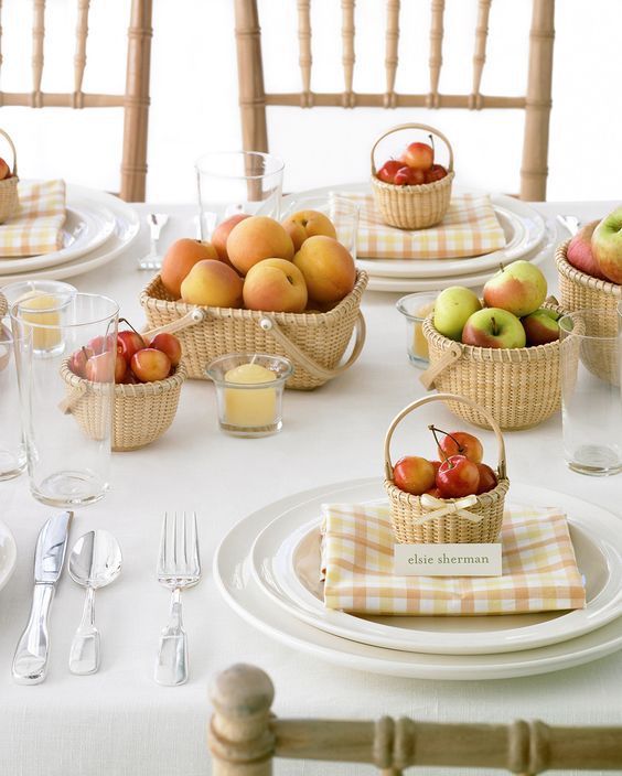 the table is set with plates, cups and bowls filled with apples in baskets on them