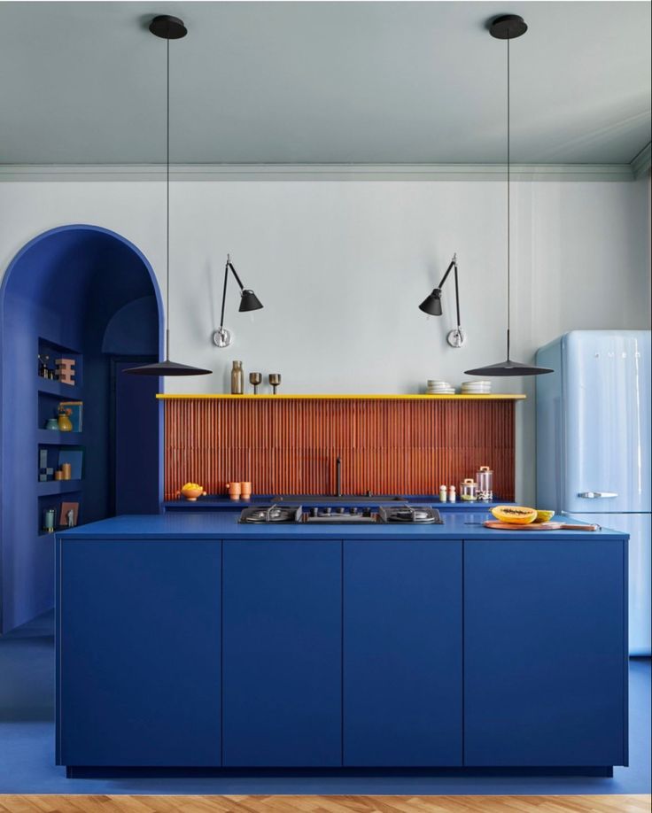 a kitchen with blue cabinets and an arch in the wall, along with wooden flooring