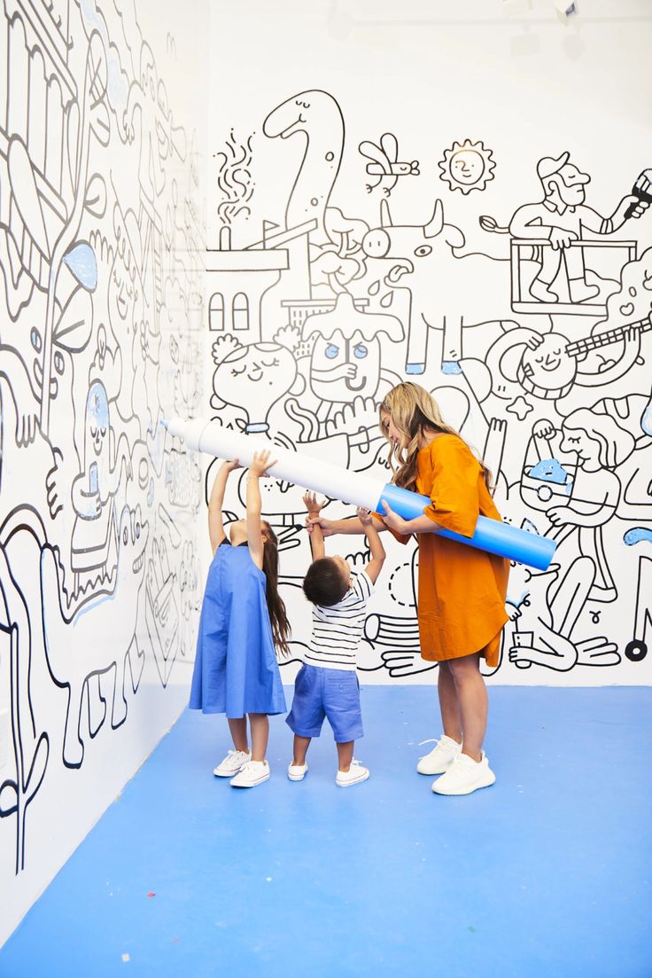 a woman and two children are playing with an inflatable tube at the museum