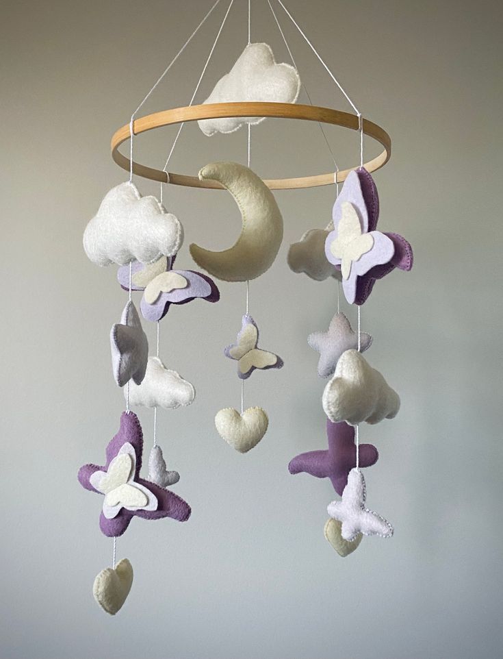 a crib mobile with white and purple butterflies hanging from it's center circle