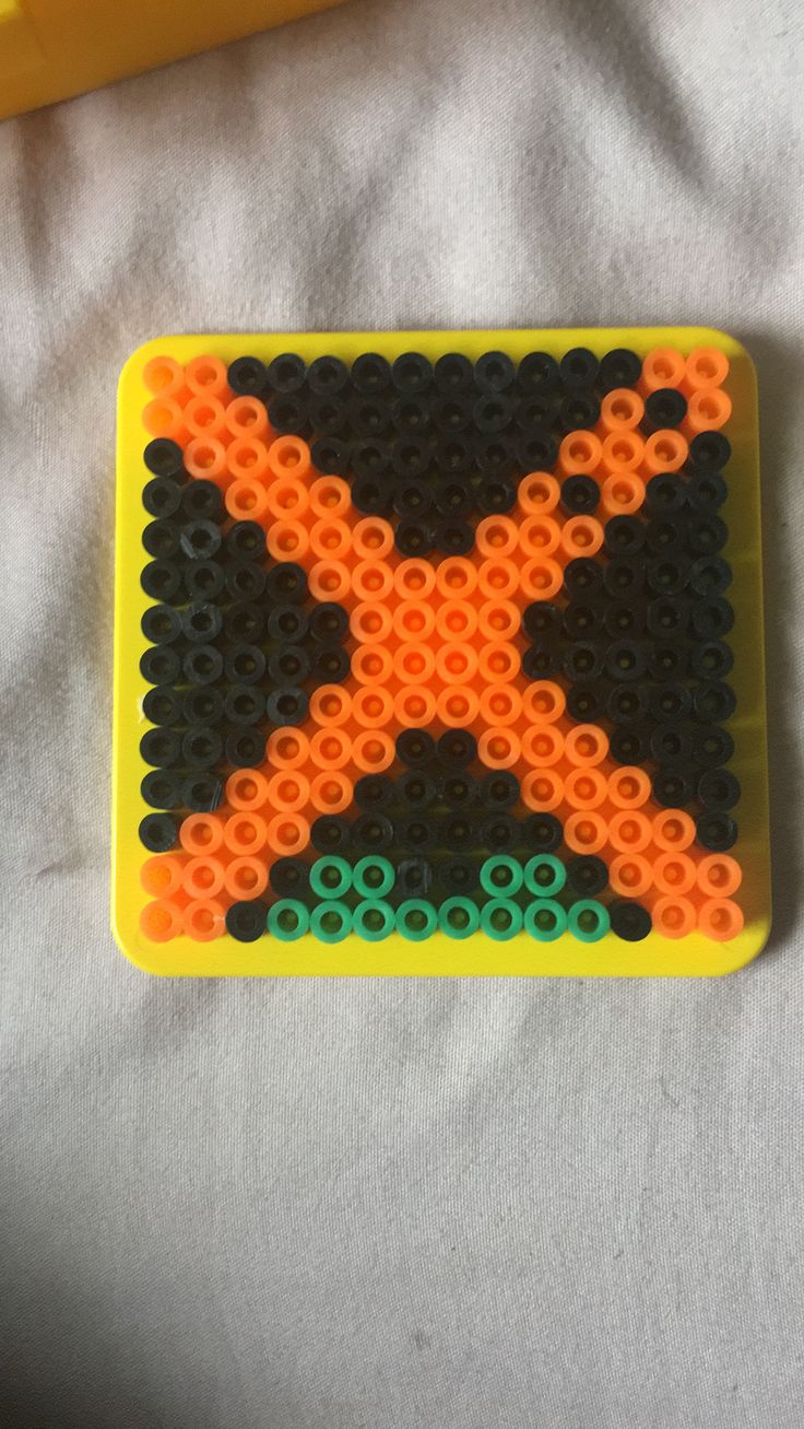 an orange and black beaded object sitting on top of a white surface next to a yellow plastic tube