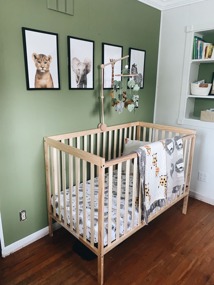 a baby's crib in a green room with pictures on the wall