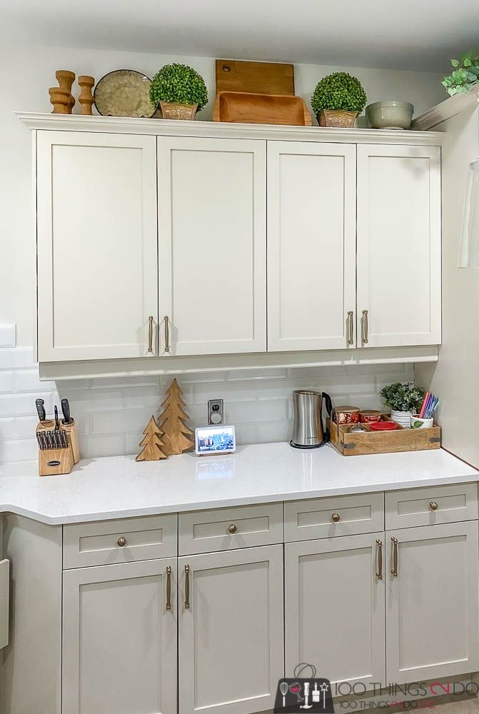 a kitchen with white cabinets and wooden utensils on the top shelf above it