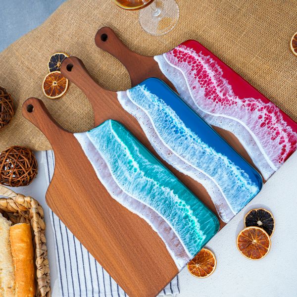 two wooden cutting boards sitting on top of a table next to bread and orange slices