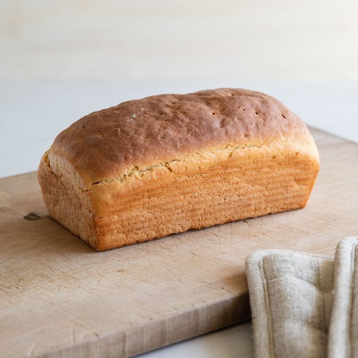 a loaf of bread sitting on top of a wooden cutting board next to a cloth