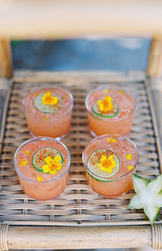 four desserts are sitting on a wicker tray with flowers in the middle and one is empty